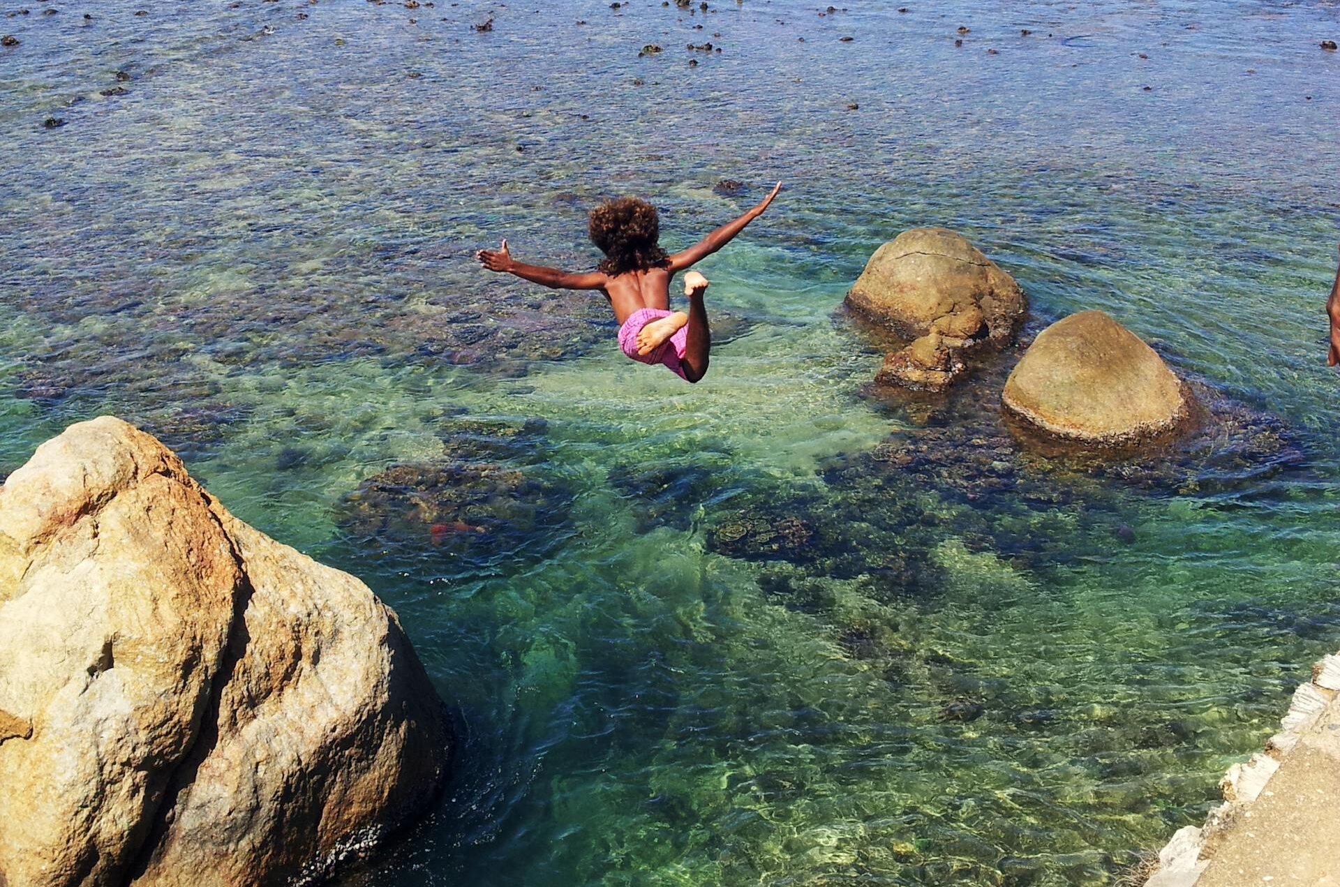 Child Diving Off Cliff Into Sea